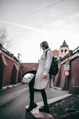 a hipster girl in a coat and gathered hair walks around the city