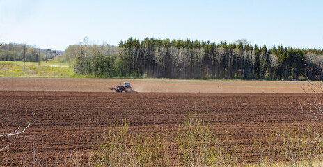 tractor plows the field on a sunny spring day