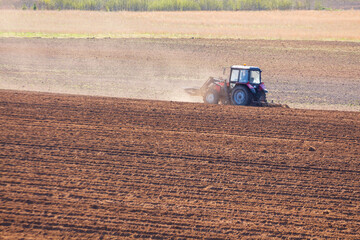 tractor plows the field on a sunny spring day