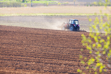 tractor plows the field on a sunny spring day