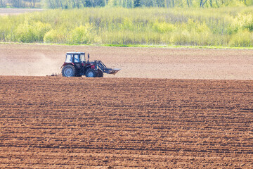 tractor plows the field on a sunny spring day