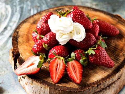 eine baumscheibe mit frischen s&uuml;&szlig;en erdbeeren und einem klecks sahne