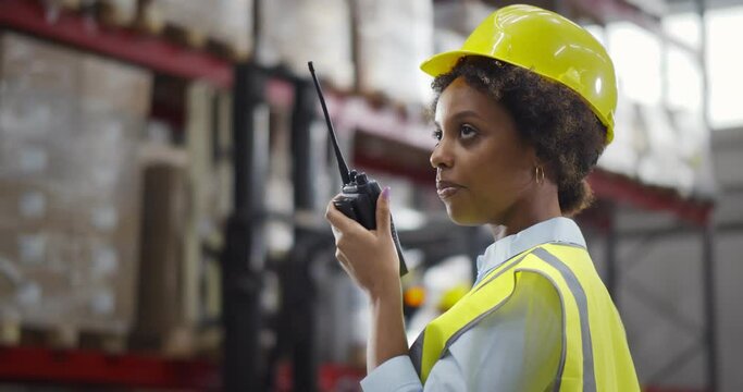 Afro-American female worker of warehouse reporting through walkie-talkie