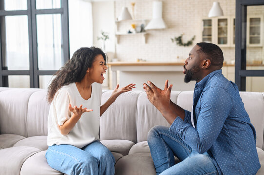 Multiracial couple is arguing at home. Angry young spouses screaming and misunderstanding to each other, African-American couple has relationships problem