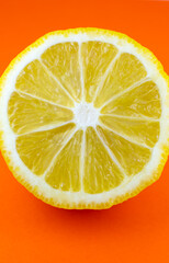 Close up photo of lemon texture on the orange background. Fruit cut in half, inside, macro view. Minimalism, original beautiful wallpaper photo.
