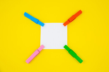 Blank white To Do List Sticker with colorful wooden clothespins. Close up of reminder note paper on...