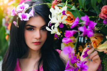 Obraz na płótnie Canvas Beauty young asian woman portrait Beautiful girl has beautiful face, long hair Attractive lady stand near flowers at garden Gorgeous female look at camera She has nice facial skin She love nature
