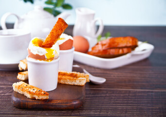 boiled egg in eggcup on wooden board with crispy toast.