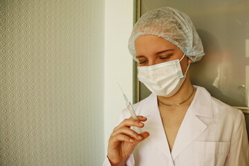 Female Doctor Or Nurse In Mask Holding Syringe
