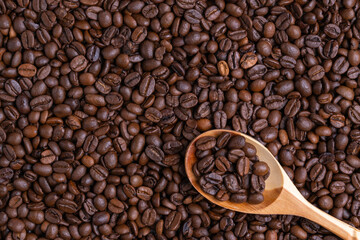 Light wooden spoon lies on coffee beans, coffee beans inside the spoon