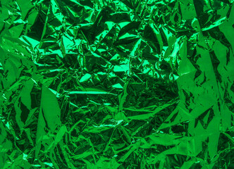 A sheet of green shiny crumpled foil. View from above. Background. Holiday. Christmas. New Year. 