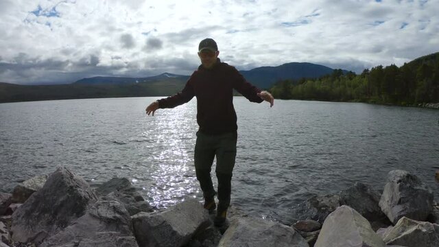 Male hiker standing on rocks in front of a lake in Saltoluokta, Northern Sweden.