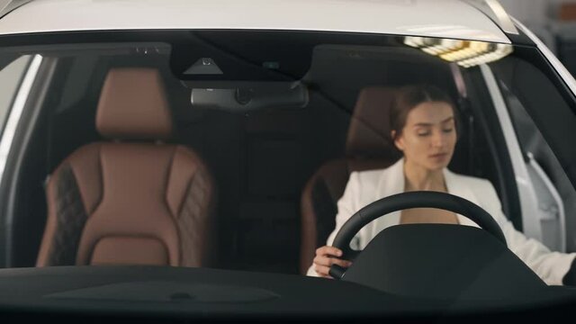 Stylish business woman sitting behind the wheel evaluates the new interior
