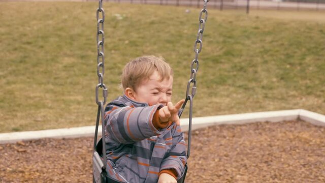 Toddler boy crying in a swing.