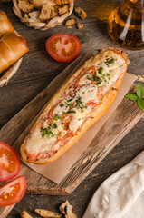 Loaf stuffed with cheese and tomatoes on a wooden background, fast food