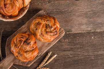 Fresh baked goods - delicious wicker buns with poppy seeds with copy space on a wooden