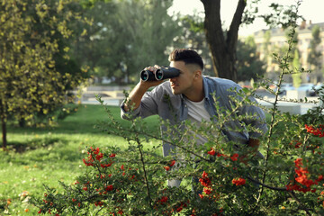 Jealous man with binoculars spying on ex girlfriend in park