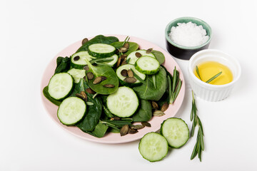 green fresh salad of spinach and cucumber and pumpkin seeds. close-up, white background