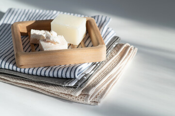 natural handmade soap on a wooden soap dish, side view, on a bath towel, light background