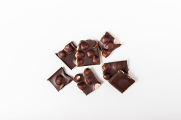 pieces of dark chocolate with whole nuts on the white background