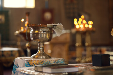Silver vessel with holy water and brush on stand in church, space for text. Baptism ceremony