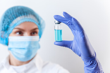 Doctor in gloves and mask holds bottle with vaccine, medicine