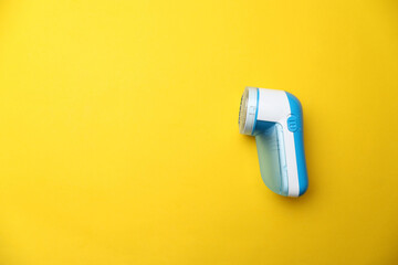 Modern fabric shaver on yellow background, top view. Space for text