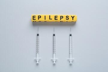 Blocks with word Epilepsy and syringes on light background, flat lay