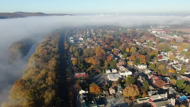 Airplane view of thick fog cloud over American neighborhood. Small town America during autumn fall foliage.