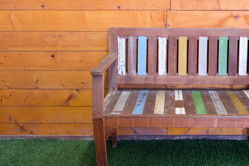 The painted wooden bench with the pastel color on the artificial grass.