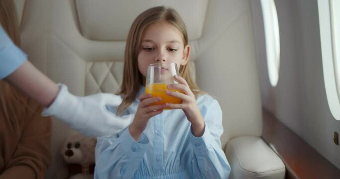 Flight attendant serving glass of orange juice for preteen girl passenger