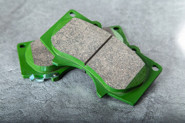 a set of new green brake pads on a gray table