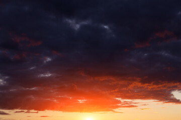 Epic dramatic sunset, sunrise on storm sky with dark clouds, orange yellow red sun and sunlight background texture	

