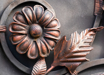 Close-up detail of beautiful vintage forged metal big yellow and red flower decorating iron gray...