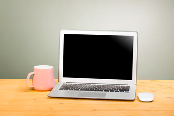 Fototapeta premium Mockup blank laptop screen with coffee on wooden table in coworking space.