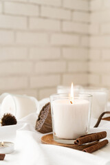 Obraz na płótnie Canvas Beautiful burning candles with cinnamon and dry flowers on white fabric background