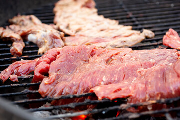 A view of cuts of beef sirloin flap cooking on a kettle grill.