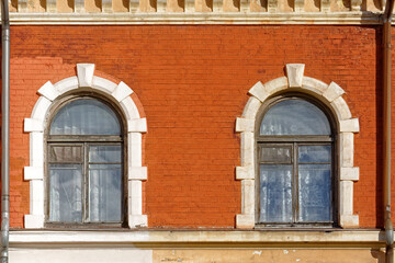 Two arched windows on a brick wall.