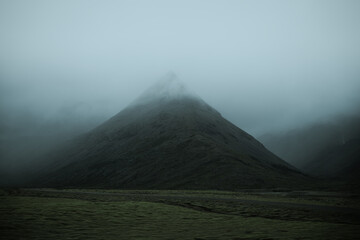 Beautiful nature dramatic landscape in Iceland. Low clouds, fog on the mountains. Cold toned filter