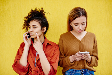 Young wistful female using mobile phones