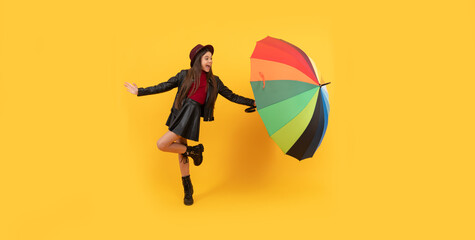 happy teen girl in hat and leather clothes having fun with rainbow umbrella, fall season