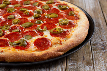 A view of a pizza pie featuring toppings as pepperoni and jalapeño.