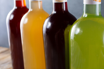 A closeup view of several brightly colored bottles of juice or alcohol, on a wooden table surface.