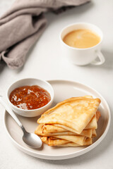 Pancakes or crepes in a plate and jam on the table. Tasty breakfast