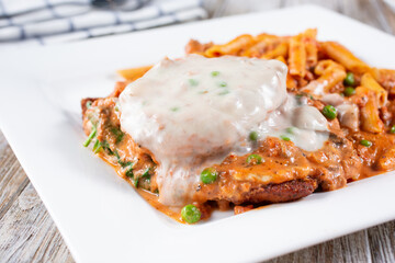 A view of chicken parmigiana and penne pasta.
