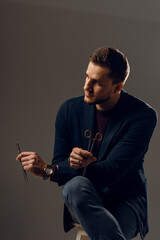 Doctor with surgical equipment needle and scissors. Handsome man weared casual business suit. Portrait of surgeon in studio