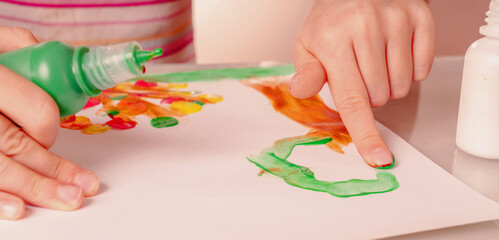 Beautiful young girl painting artwork with colorful hands and finger. Horizontal image.
