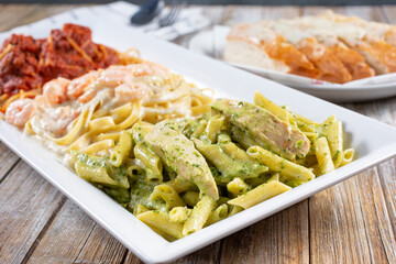 A view of a combo plate of chicken pesto, fettuccine alfredo, and spaghetti marinara.