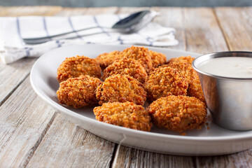 A view of a plate of deep fried ravioli or pickles, with a cup of ranch dressing.