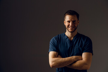 Fototapeta premium Surgeon weared in medical robe on dark background. Handsome doctor posing in studio
